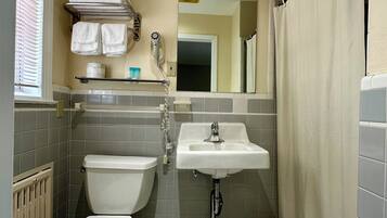 Un baño pequeño con inodoro, lavamanos y zona de ducha.