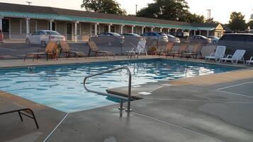 Une piscine avec des chaises longues et une clôture.