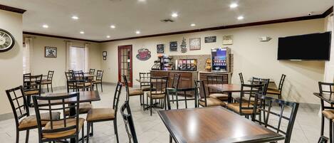 A restaurant with multiple tables and chairs, a bar area, and a clock on the wall.
