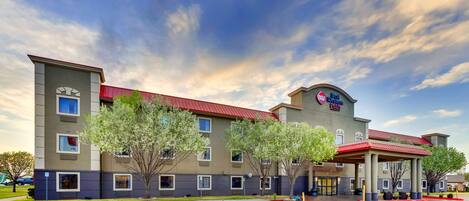 A hotel with a red roof and a 'Best Western' sign, featuring a covered outdoor area and a parking lot.