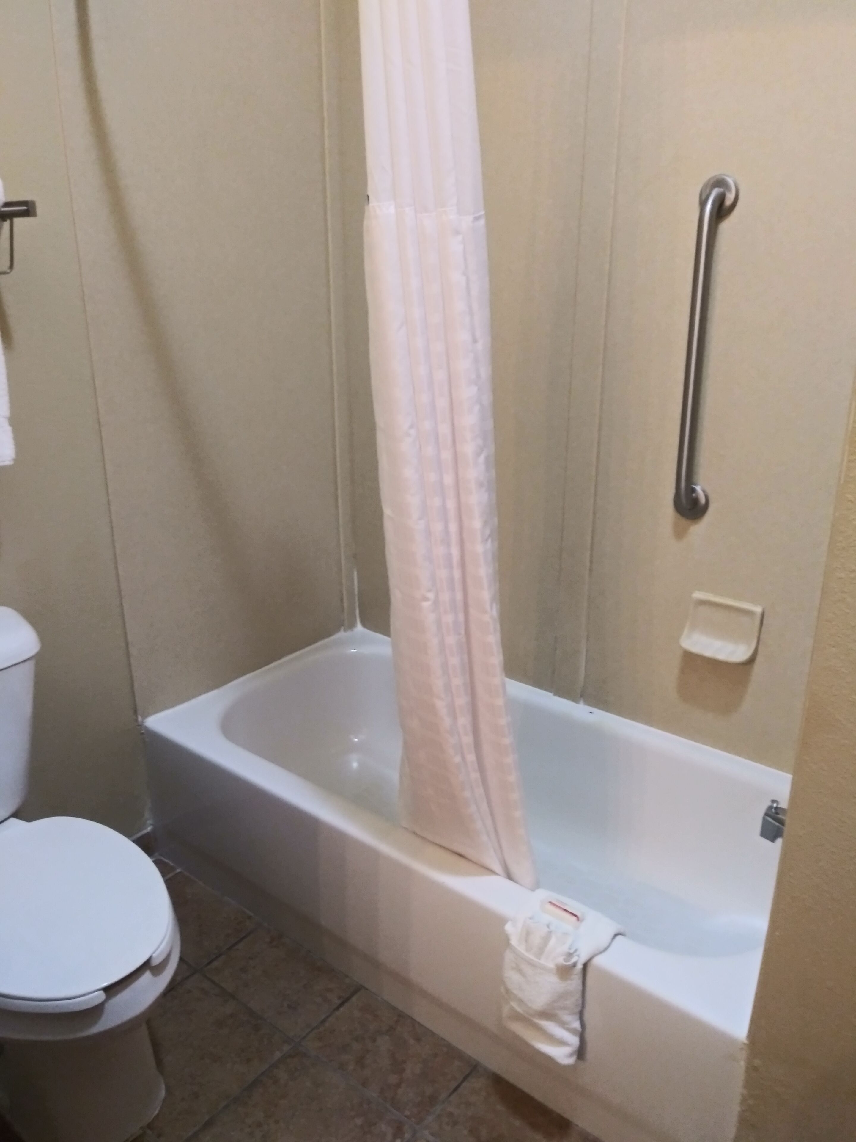 Un baño con bañera, inodoro y cortina de ducha.