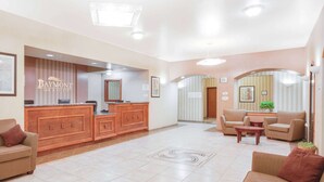 Un vestíbulo de hotel con mostrador de recepción, sofás y una pequeña mesa.