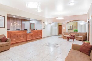 Un vestíbulo de hotel con mostrador de recepción, sofás y una pequeña mesa.