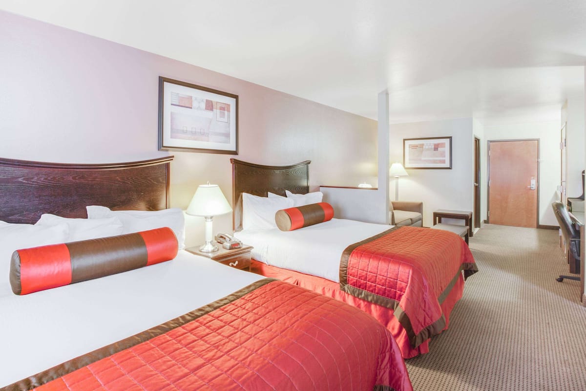 Een hotelkamer met twee bedden, een bureau, een stoel en een deur.