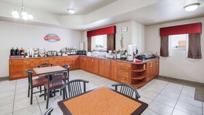 Rincón de desayuno con mostrador de madera, sillas y una mesa.