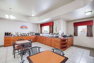 Rincón de desayuno con mostrador de madera, sillas y una mesa.