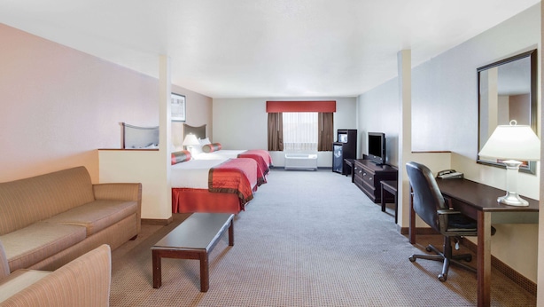 Una habitación de hotel con cama, sofá, escritorio, silla, televisor y lámpara de escritorio.