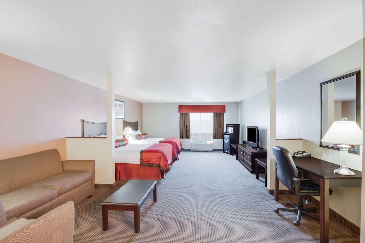 Hotelkamer met een bed, een bank, een bureau, een stoel, een televisie en een bureaulamp.