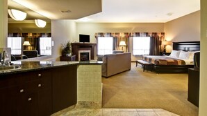 Habitación de hotel con kitchenette, sofá, cama y chimenea.
