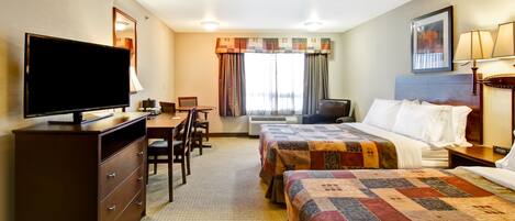 Habitación de hotel con dos camas, un escritorio, un televisor y una ventana con cortinas.