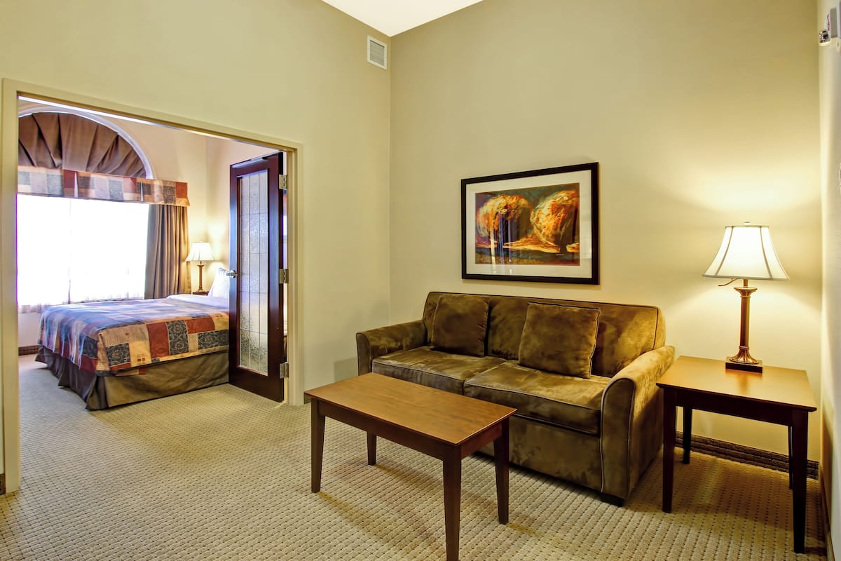 A hotel room with a bed, a sofa, a coffee table, and a lamp.