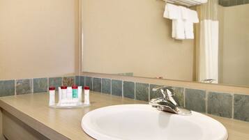 A bathroom with a white sink, a mirror, and toiletries on the counter.