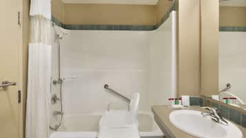 Een badkamer met een douche, een wastafel en een spiegel.