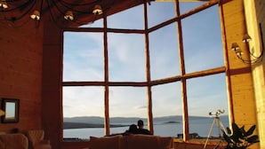 A spacious room with large windows, a wooden floor, and a tripod-mounted telescope. - Blanca Patagonia Boutique Inn and Cabins (El Calafate)