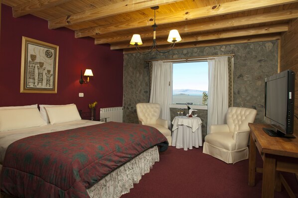 Habitación de hotel con una cama grande, dos sillones, televisión y ventana con vistas.