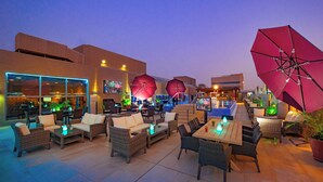 Un espace extérieur aménagé en terrasse, avec des meubles en osier, des parasols et une piscine.