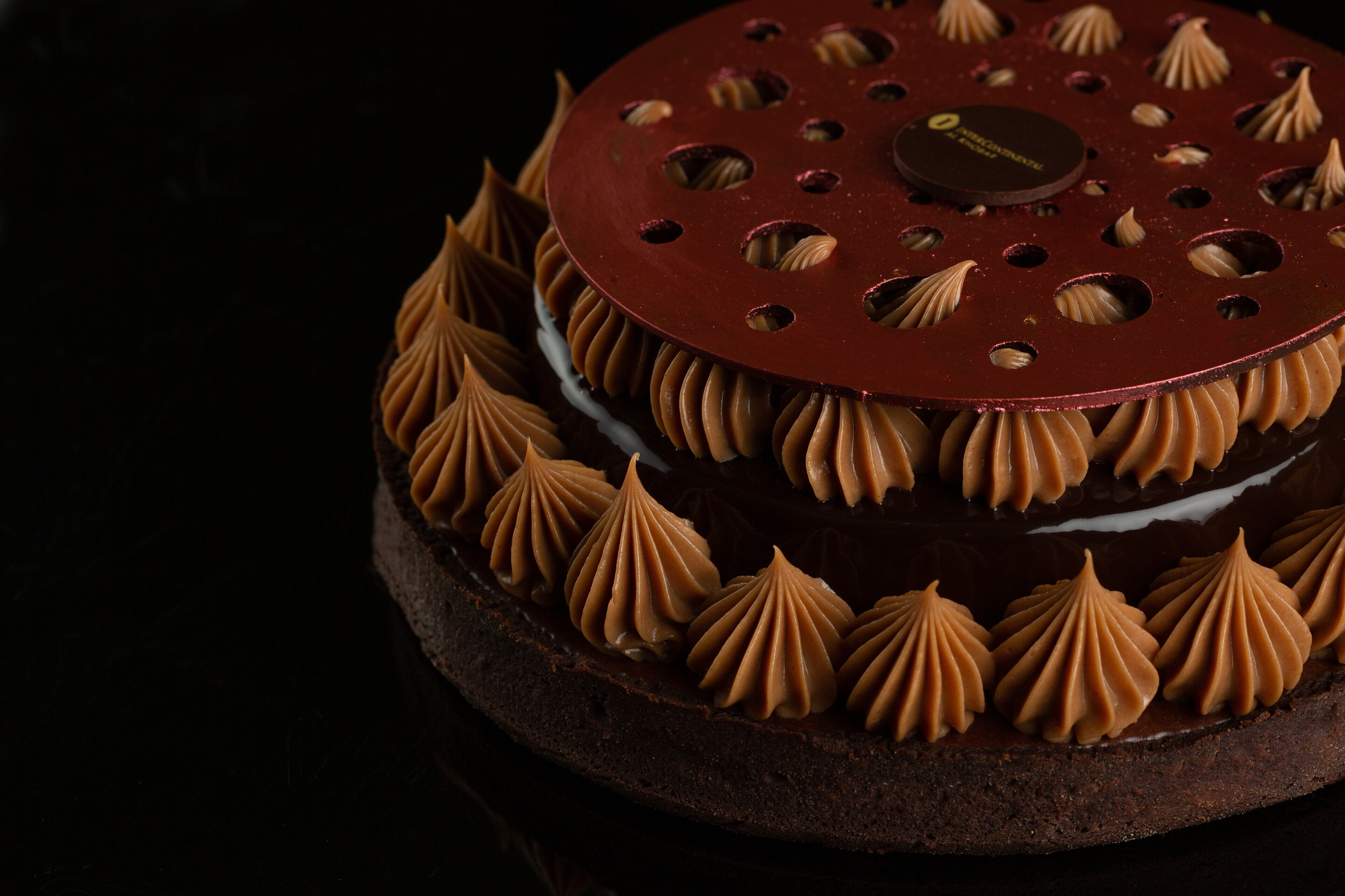 Ein Schokoladenkuchen mit Verzierung oben und runder Unterlage.