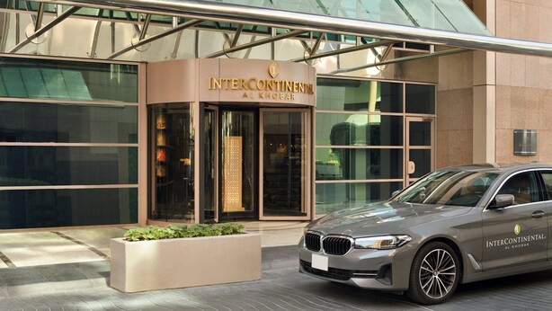 Un bâtiment moderne avec une façade en verre et une voiture BMW garée devant.
