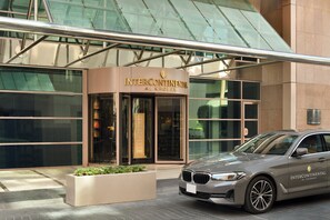 En moderne bygning med en glasfacade og en BMW parkeret foran.