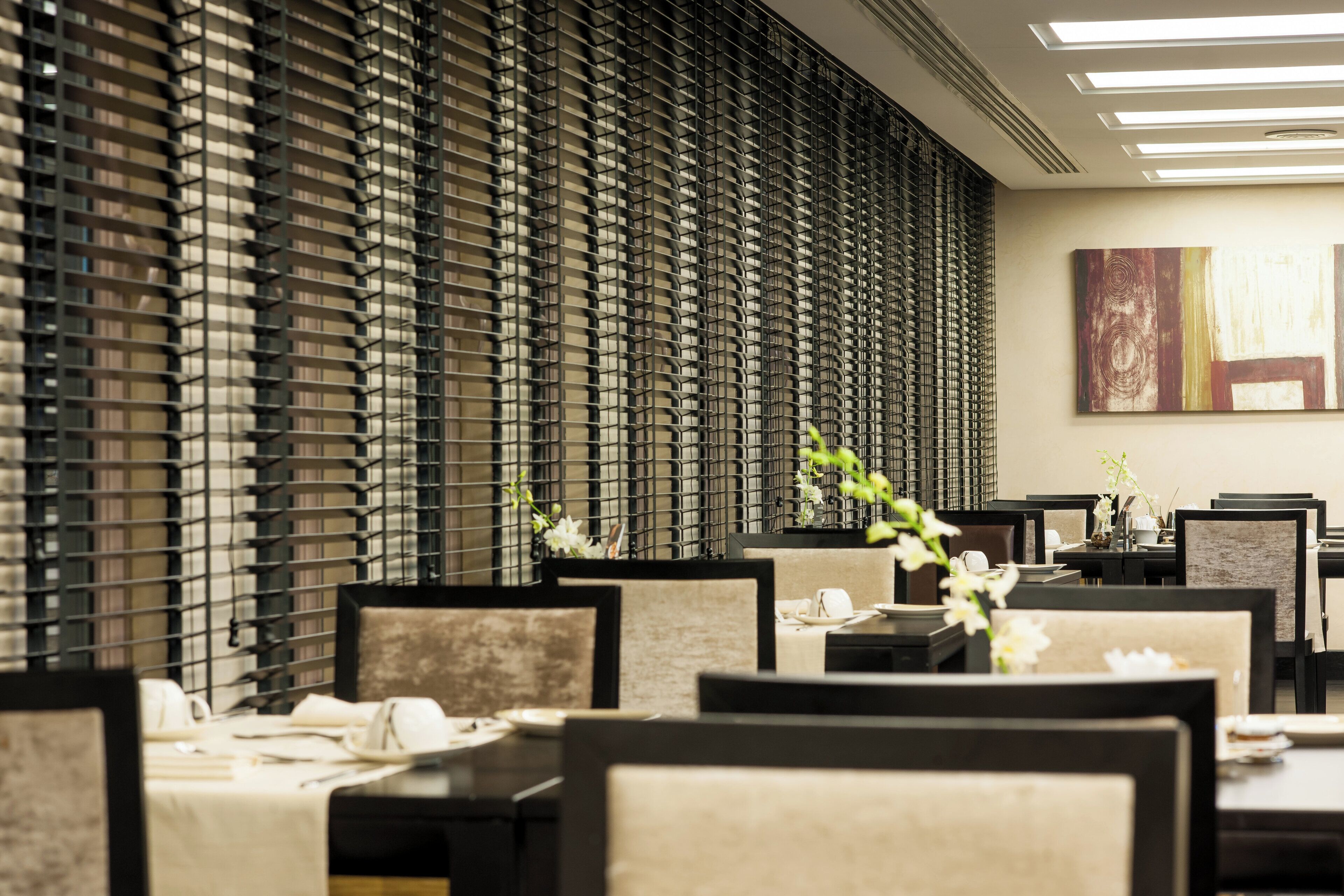 A restaurant with a modern interior featuring a patterned wall, neatly arranged tables, and chairs.