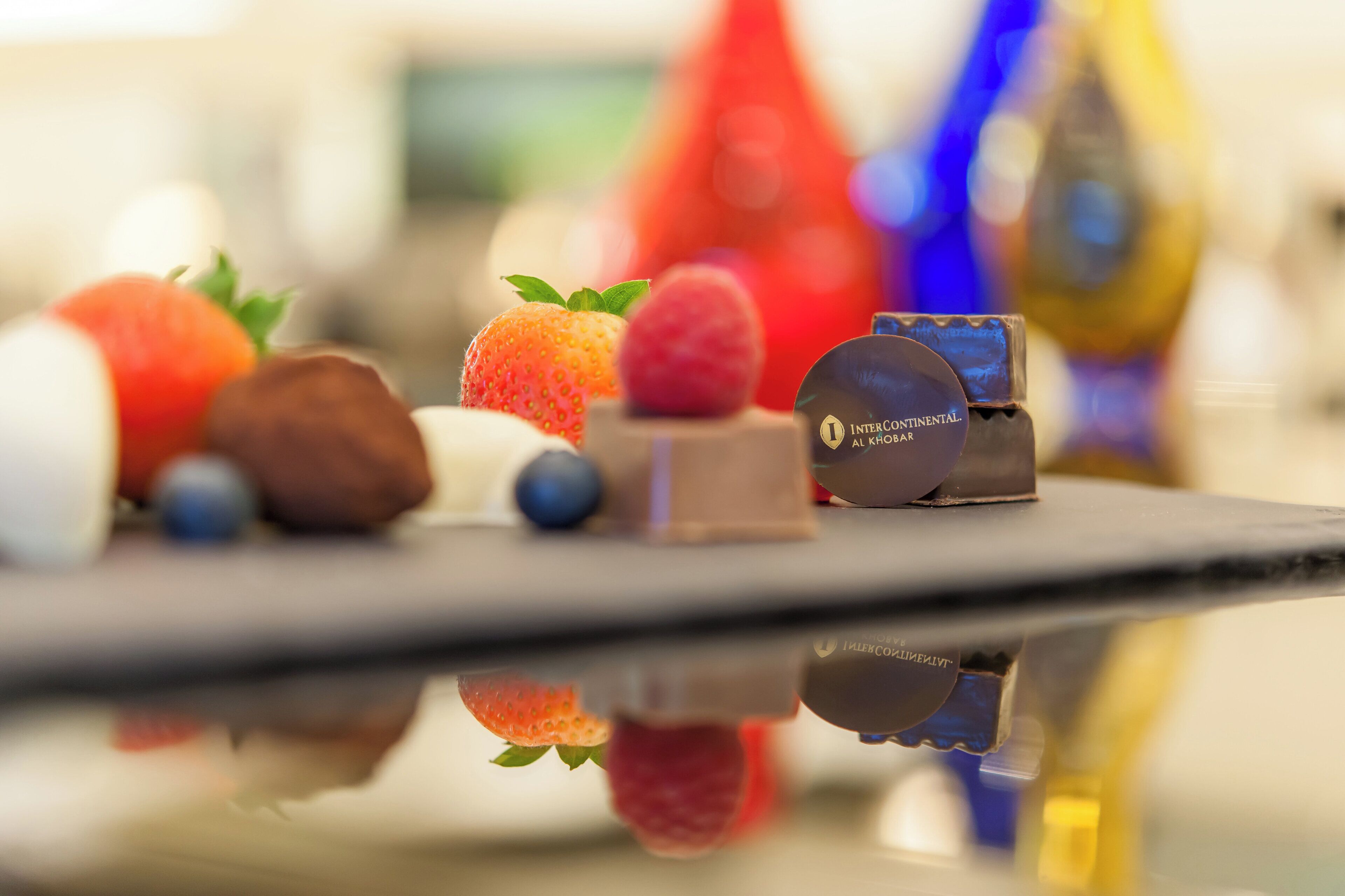 Una selezione di frutta e cioccolatini su una superficie riflettente.