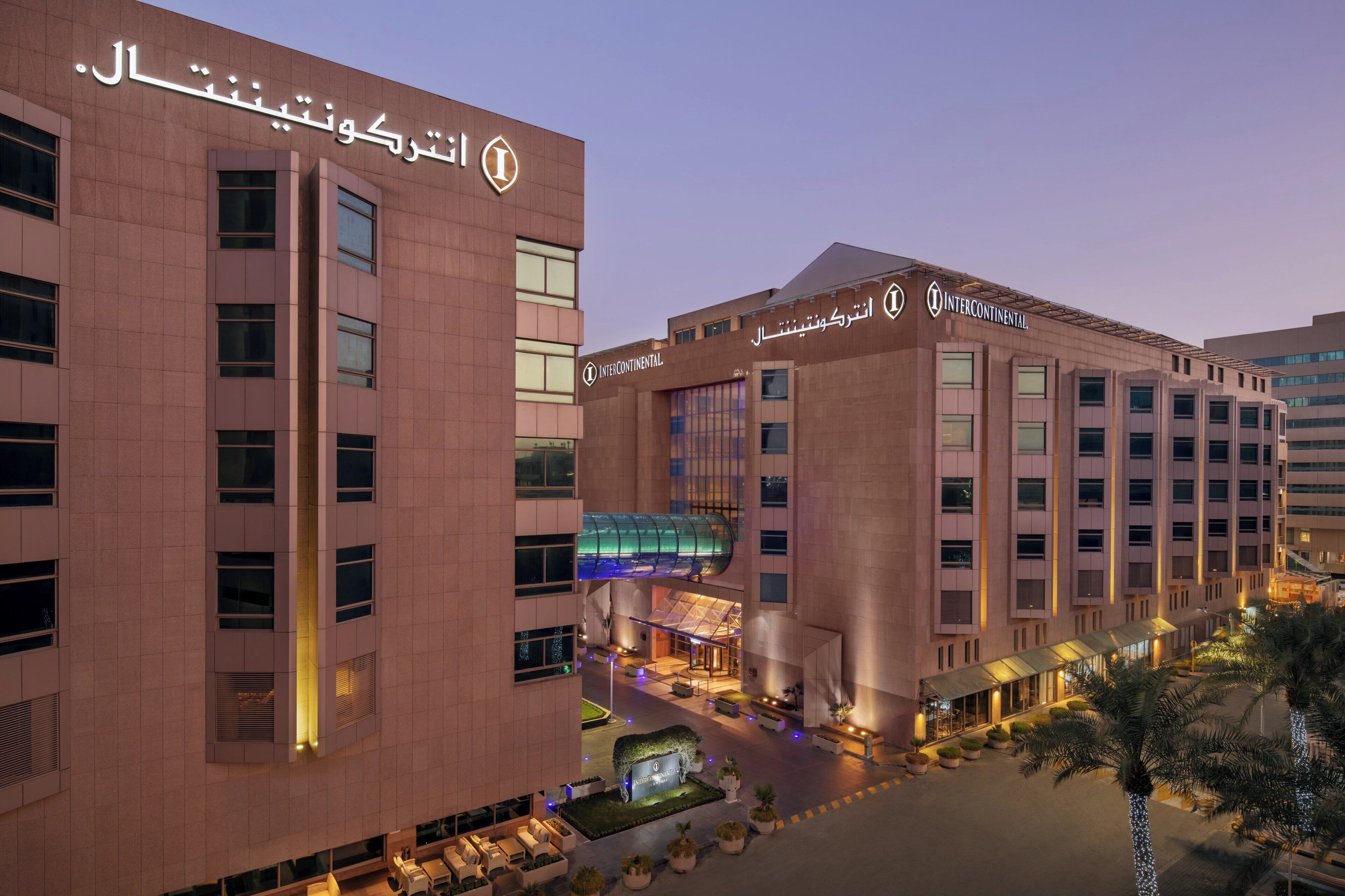 A modern hotel with a prominent entrance, multiple floors, and a covered outdoor area with seating.