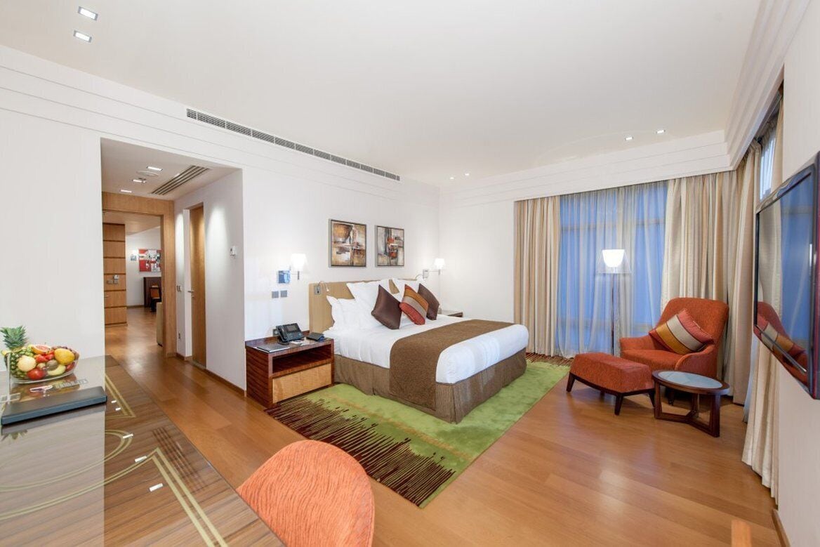Una habitación de hotel con una cama, mesita de noche, silla y una pequeña mesa.
