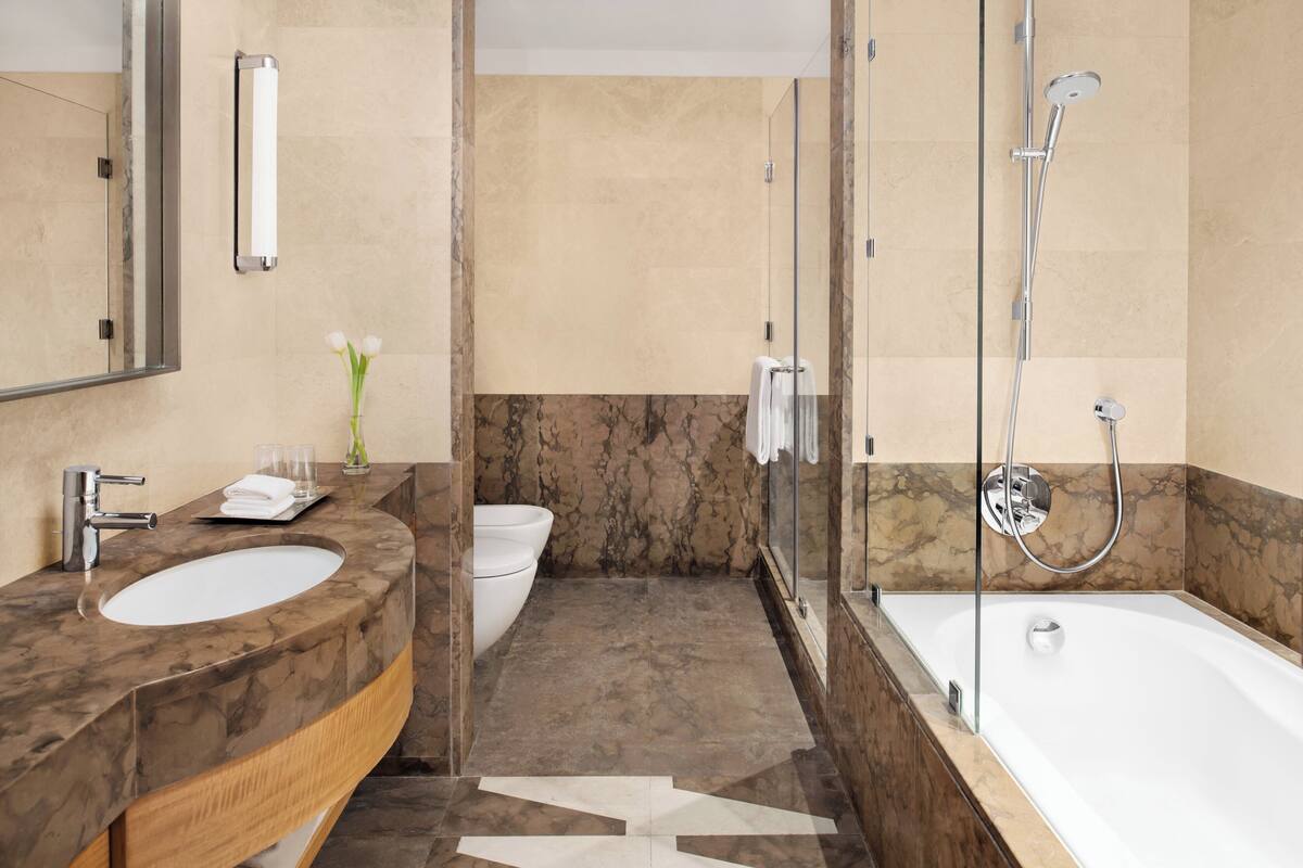 Une salle de bain moderne avec un lavabo en marbre, une douche à parois de verre et un grand miroir.