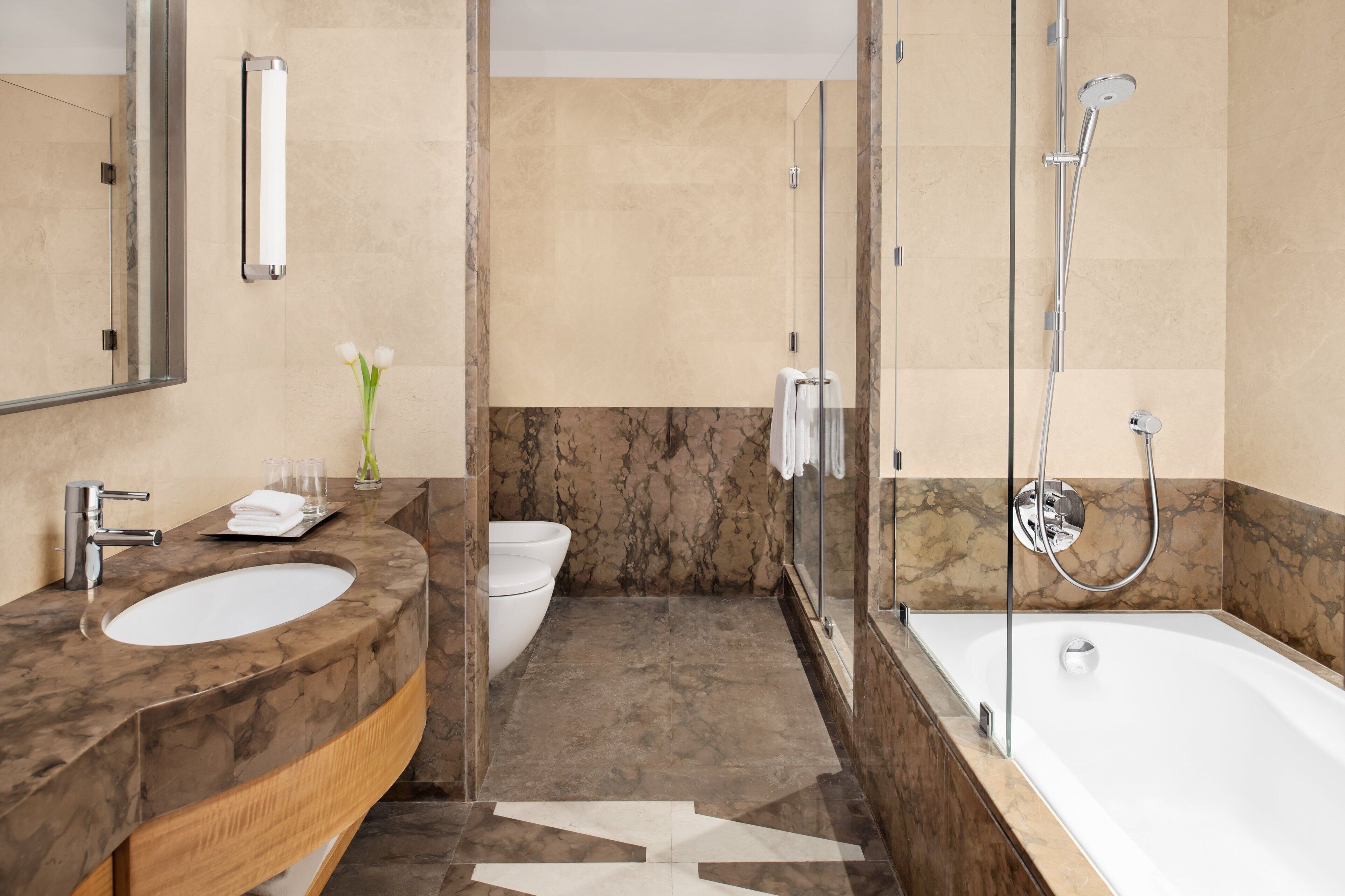A modern bathroom with a marble sink, a glass-enclosed shower, and a large mirror.