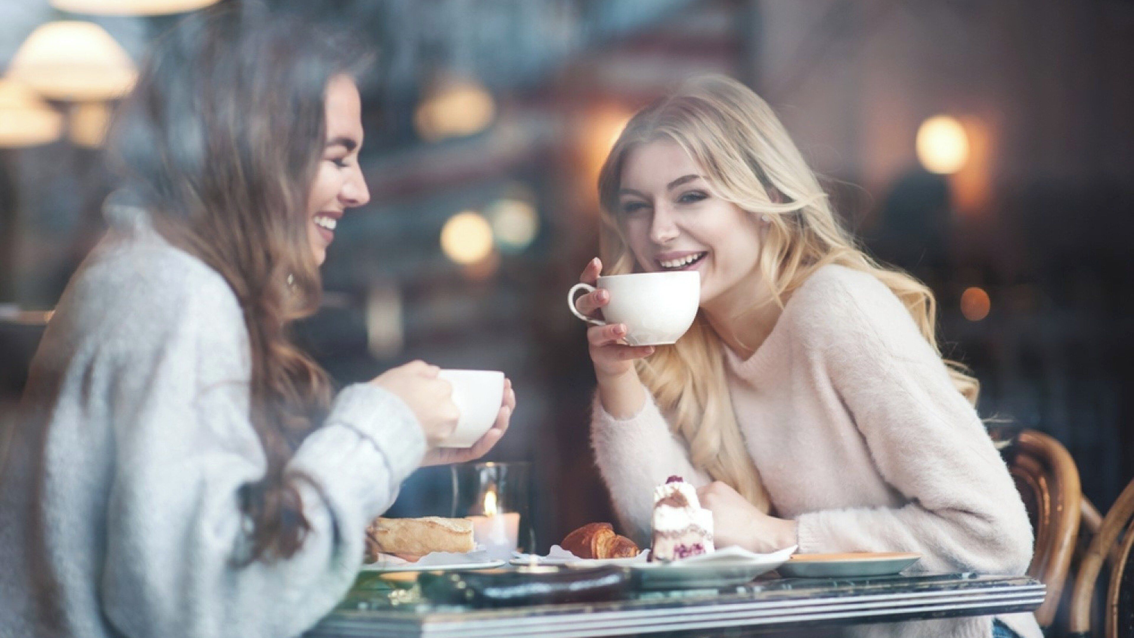 Two people sitting at a table with a cup and pastries.
