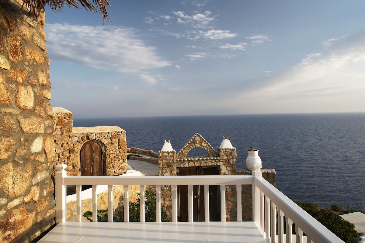 A stone building with a white balcony railing overlooking the sea.