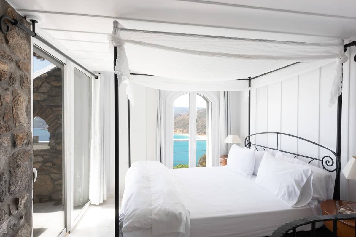 A bed with white linens, a metal headboard, and a canopy.
