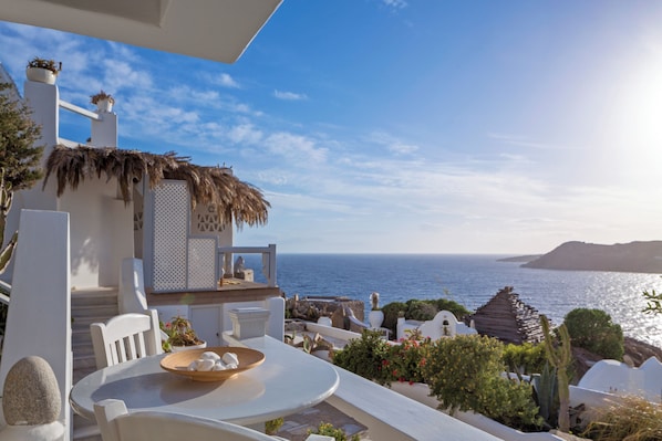 Un espacio de descanso al aire libre con mesa y sillas, con vista al mar.