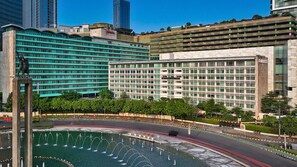 A modern hotel with a central courtyard featuring a fountain, surrounded by lush greenery and high-rise buildings. - Hotel Indonesia Kempinski Jakarta (Jakarta)