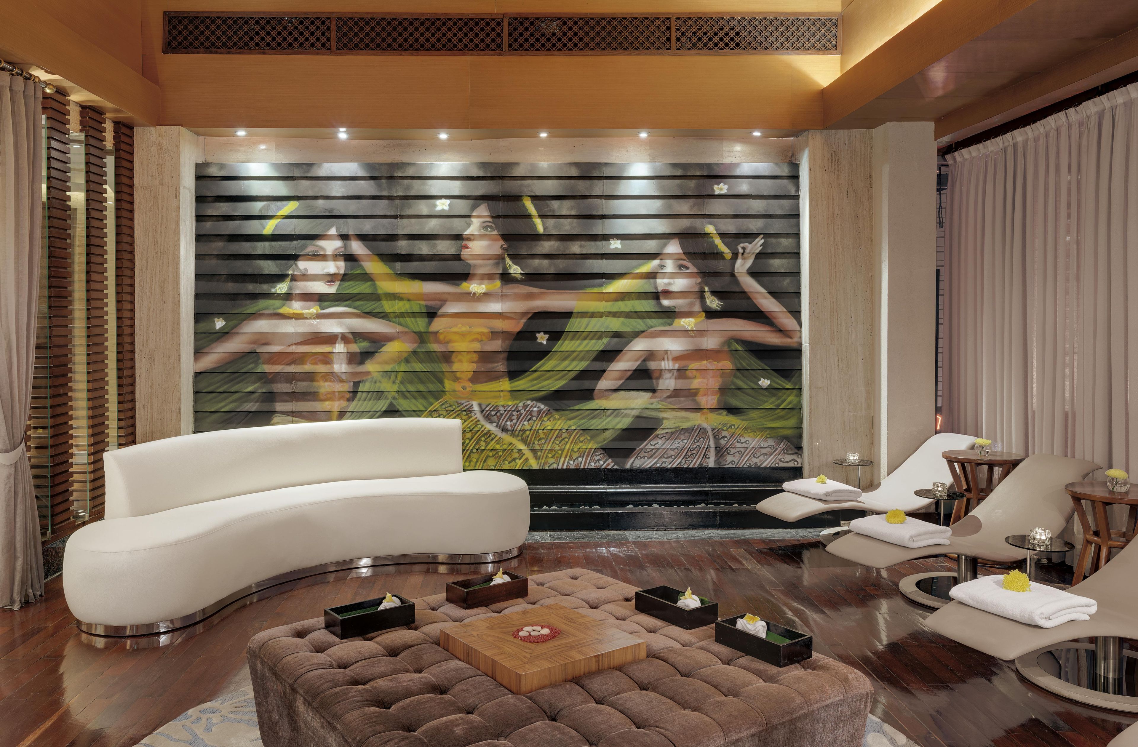 A modern living room with a curved sofa, a coffee table, and a wall with a large abstract painting.