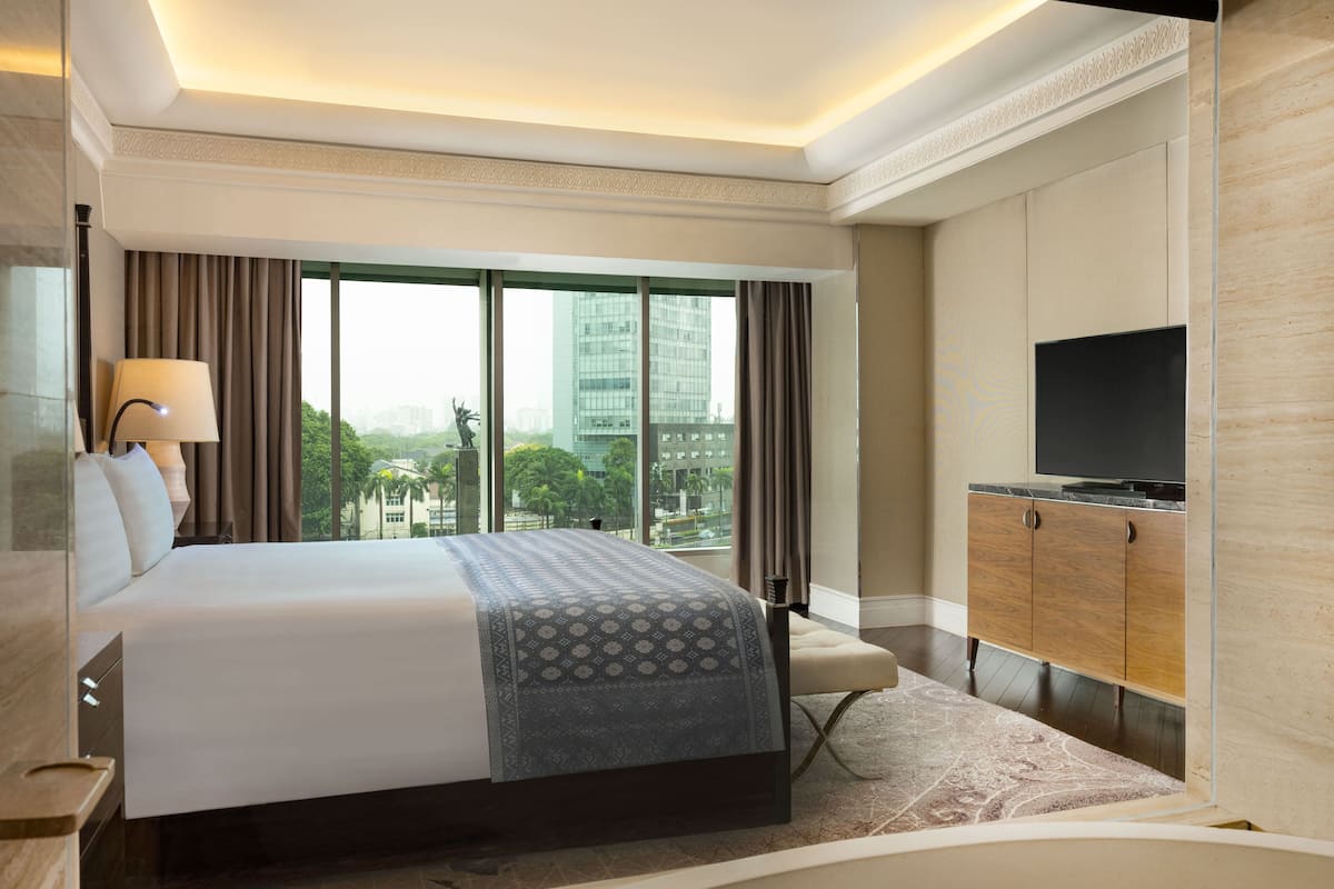 A hotel room with a large bed, a television, and a view of the cityscape.