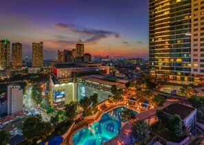 A cityscape at dusk with a prominent hotel featuring a rooftop pool and a large sign. - Hotel Indonesia Kempinski Jakarta (Jakarta)