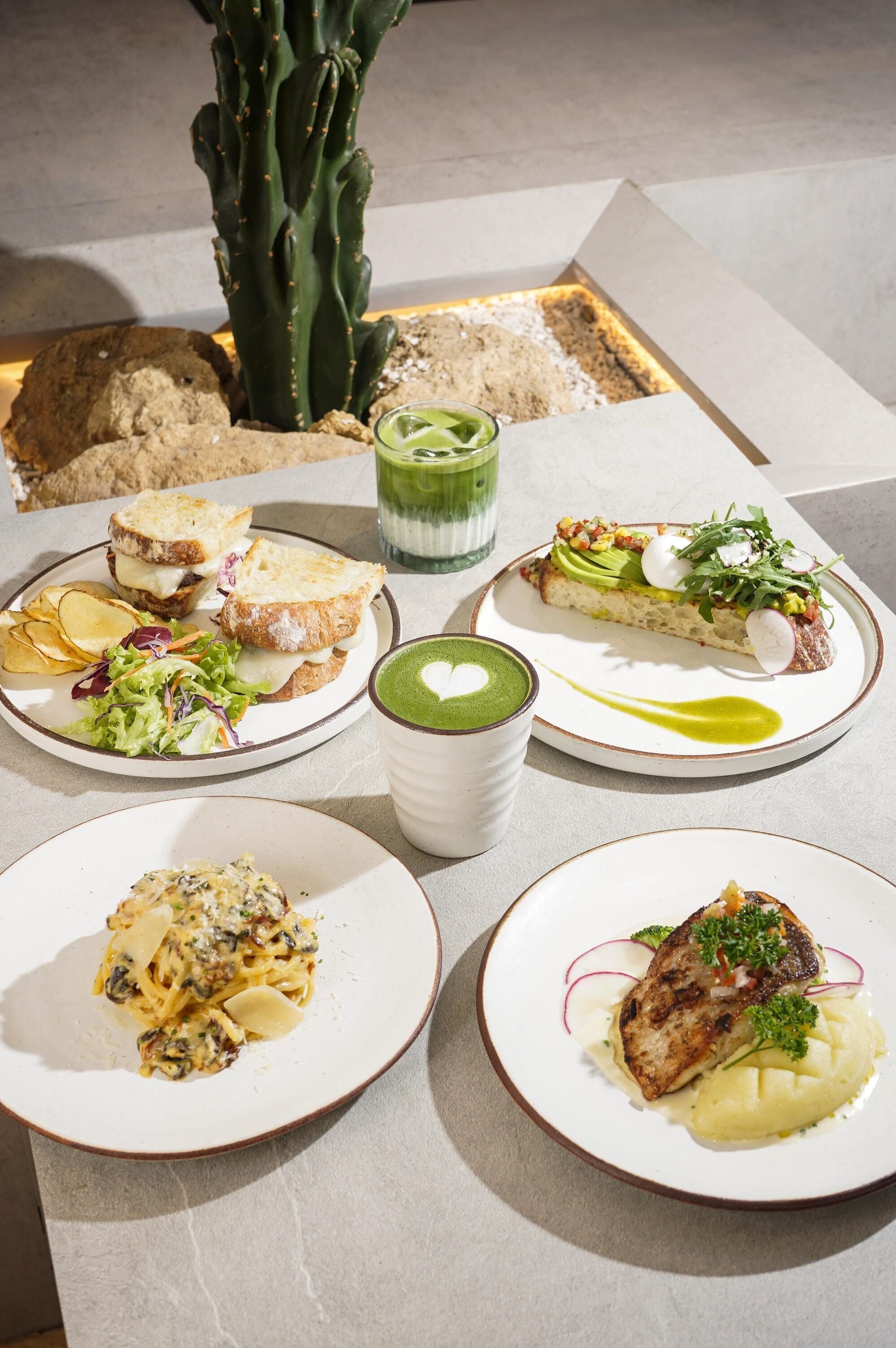 A table with various dishes, including sandwiches, pasta, and a dessert.