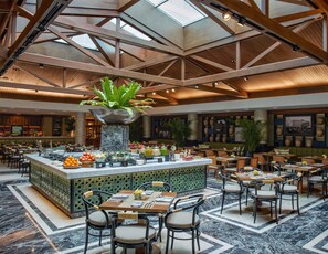A spacious hotel lobby with a central island featuring a large plant, surrounded by seating areas and a variety of amenities. - Hotel Indonesia Kempinski Jakarta (Jakarta)