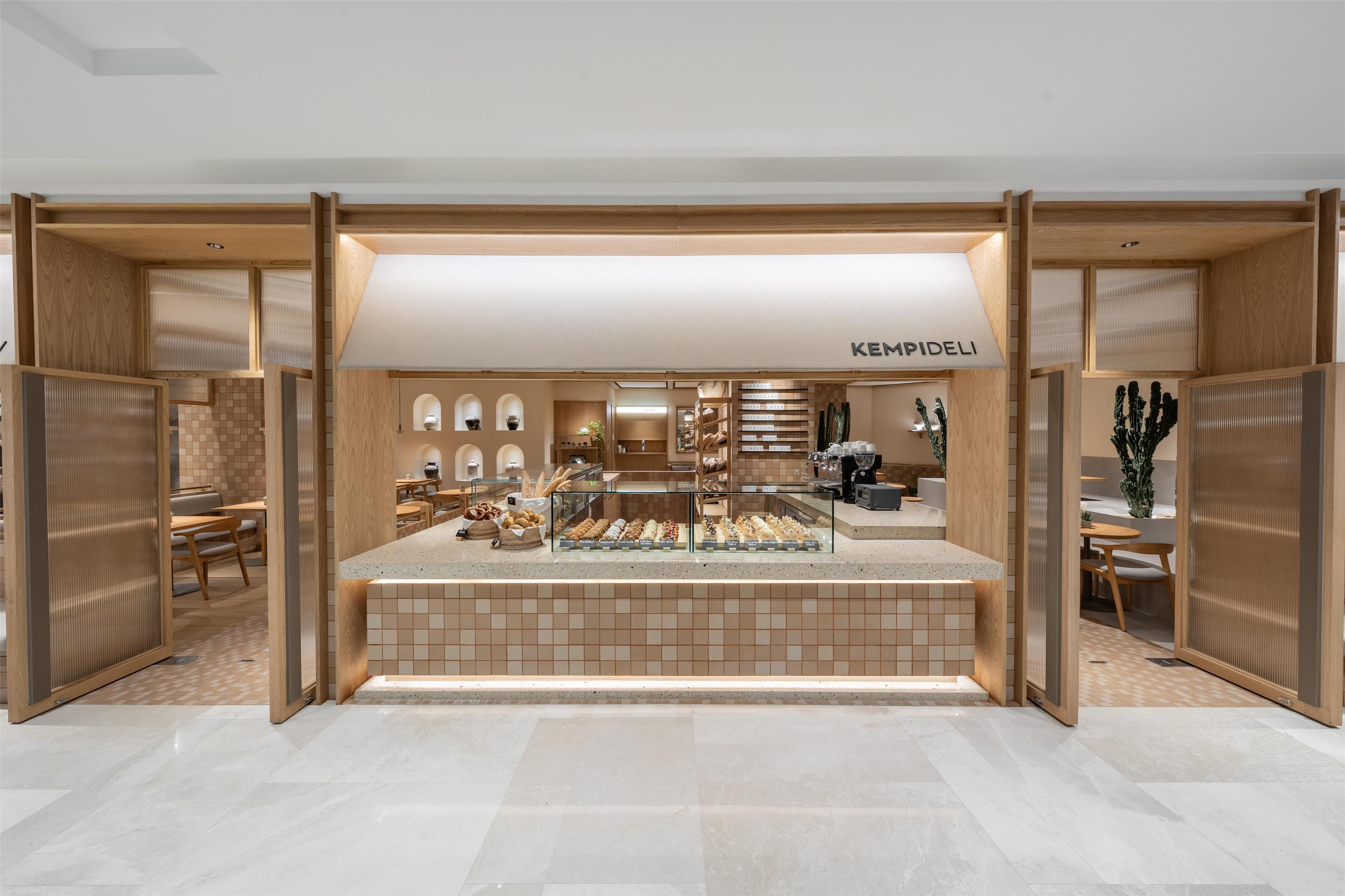 Una panadería moderna con un mostrador central de exhibición, separadores de madera y un piso limpio de baldosas.