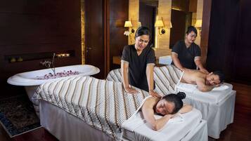 Una stanza spa con due lettini per massaggi, una vasca e uno specchio che riflette l'ambiente.