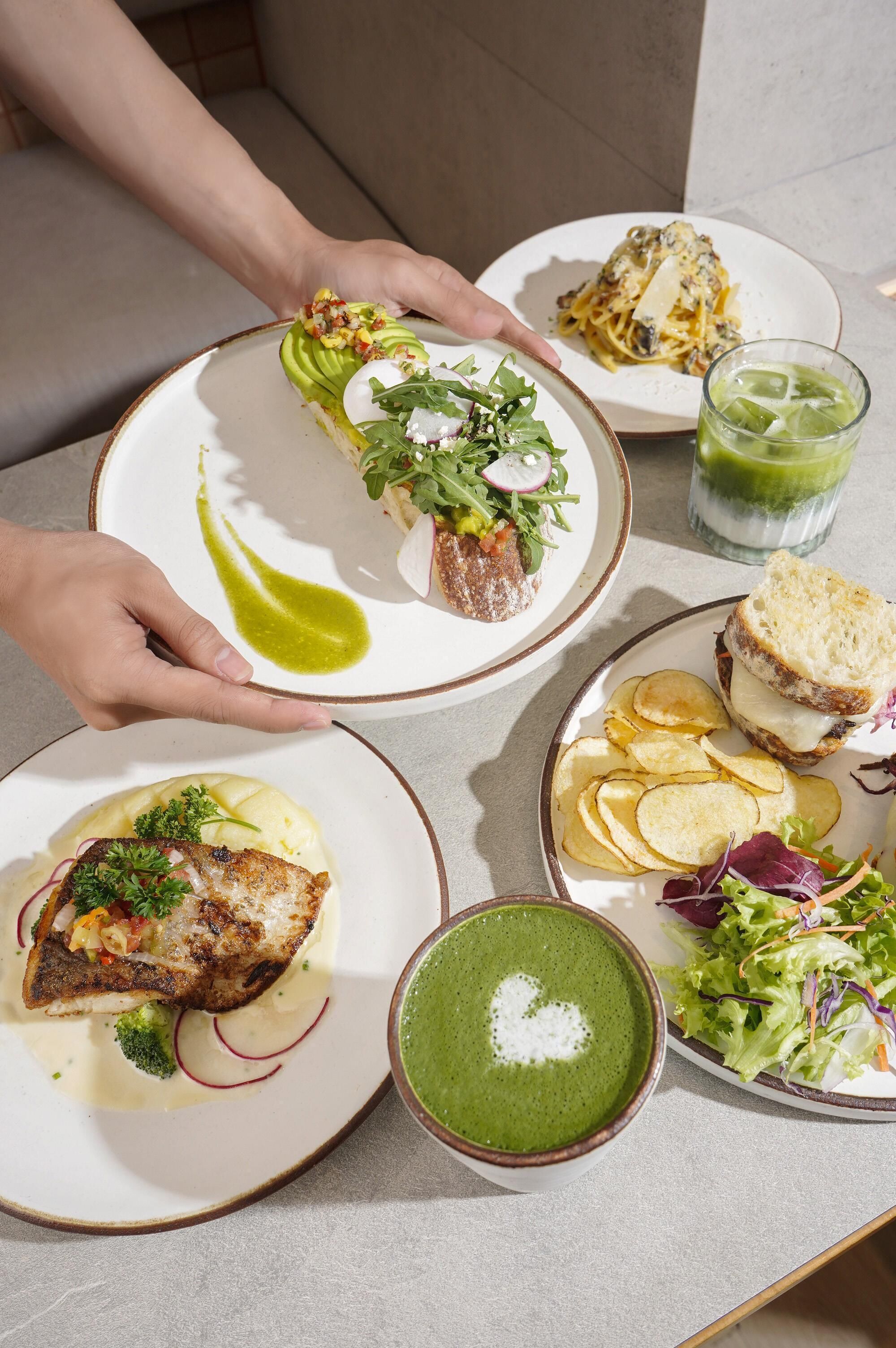 A table with various dishes including fish, pasta, and a green soup.