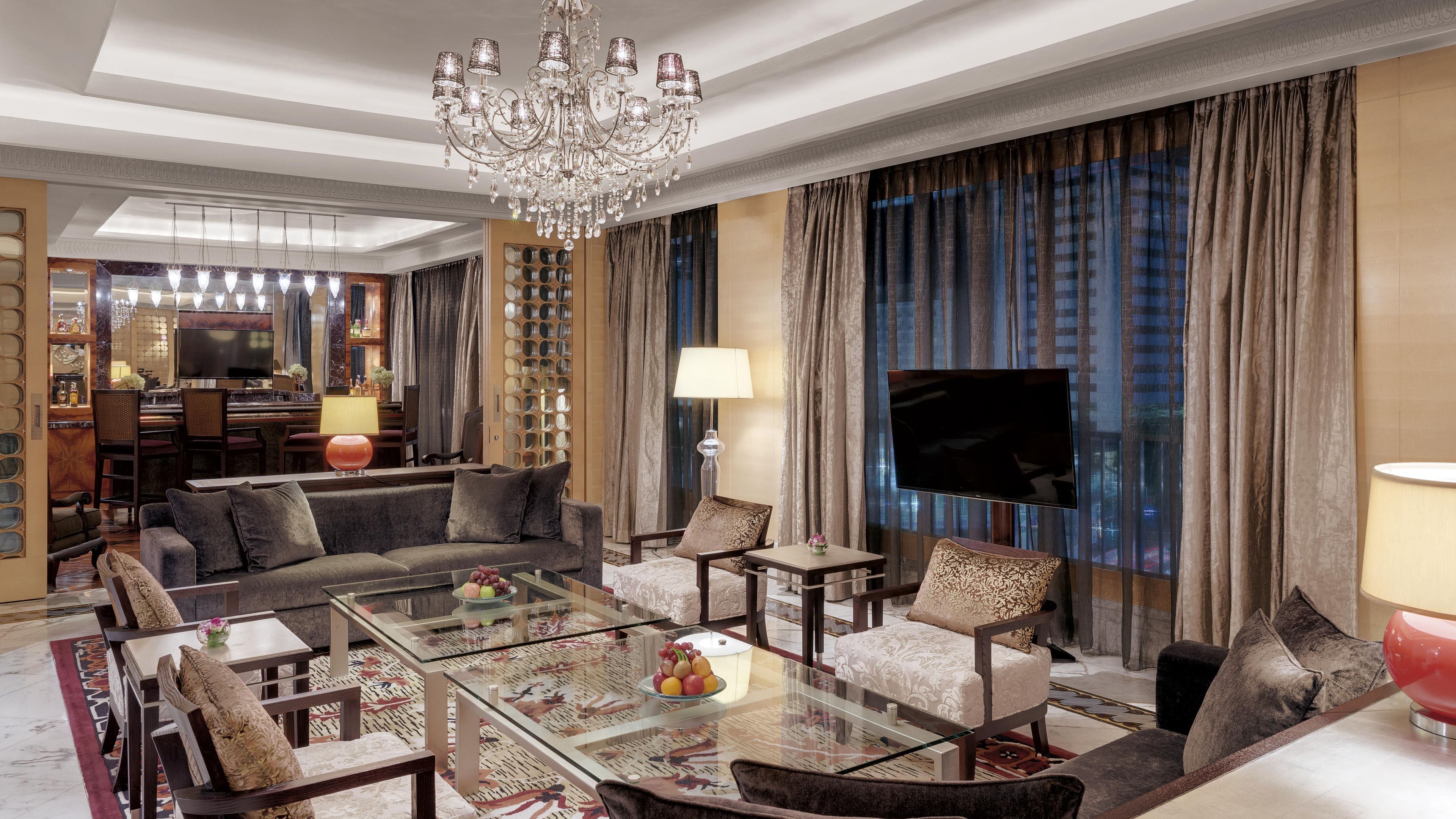 Amplia sala de estar con candelabro, televisor de pantalla plana y comedor con barra.