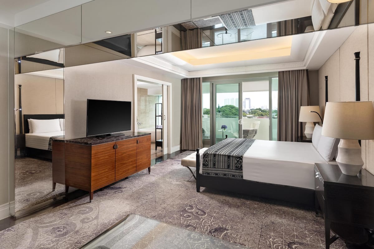 A modern hotel room with a large bed, a TV, a wooden dresser, and a balcony with a view.