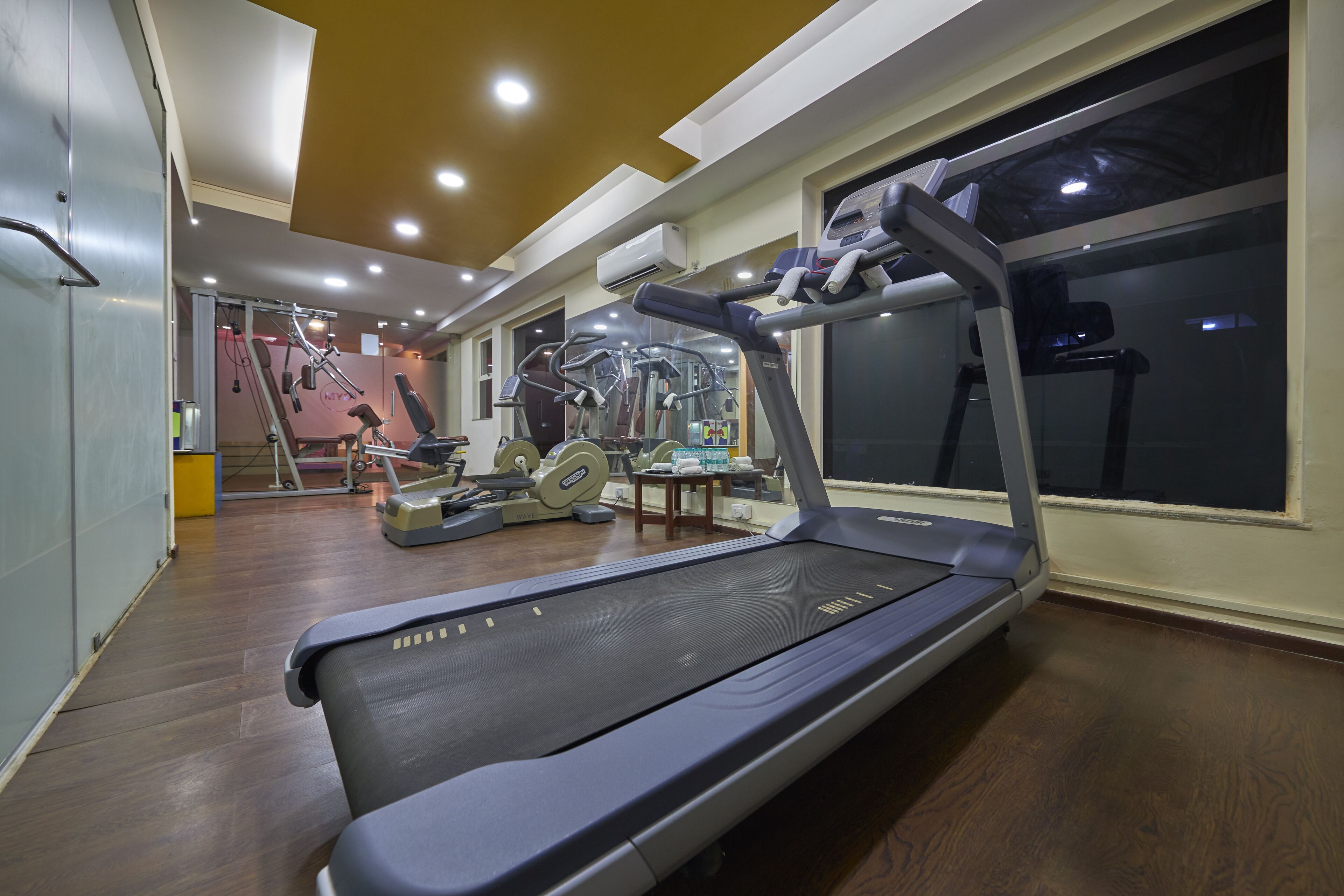 A gym with a treadmill, exercise bikes, and weights.