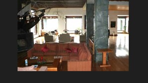 A spacious living area with a wooden staircase, a large sectional sofa, and a wooden coffee table. - Gran Hotel Vicente Costanera (Puerto Montt)