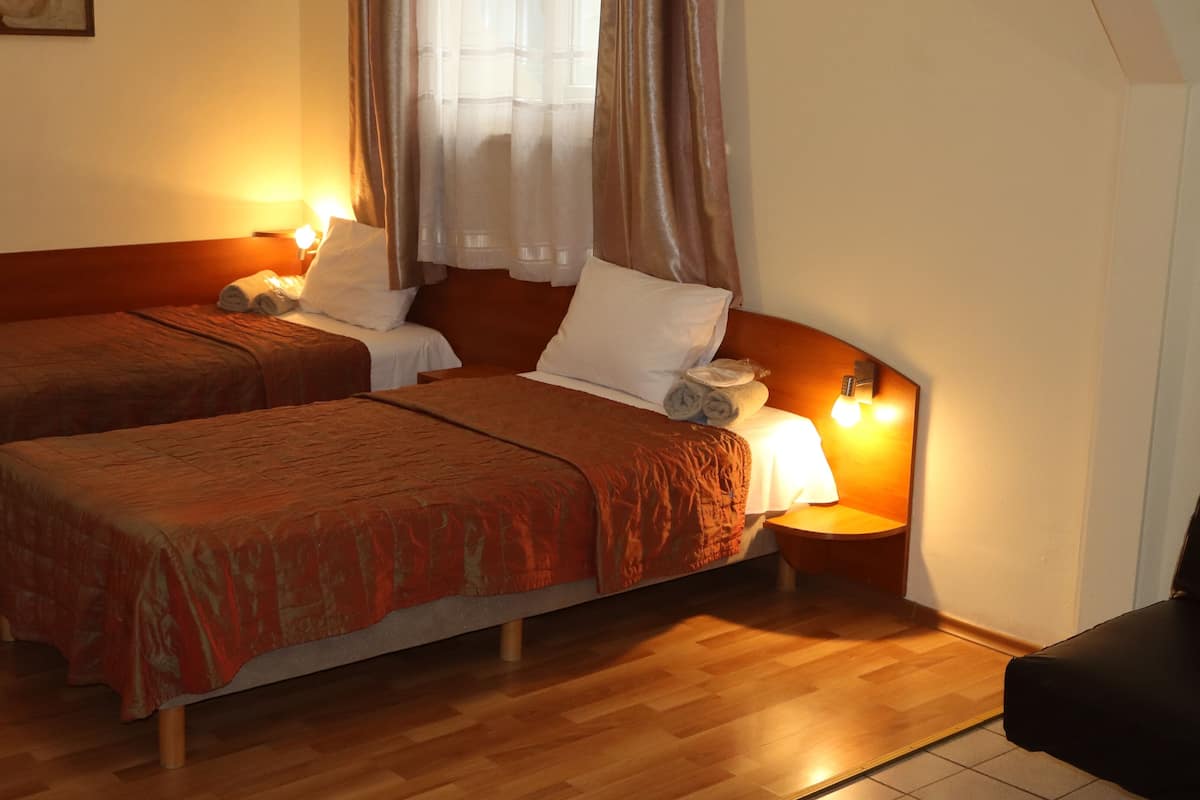 A hotel room with two beds, each with a wooden headboard, a nightstand, and a lamp.
