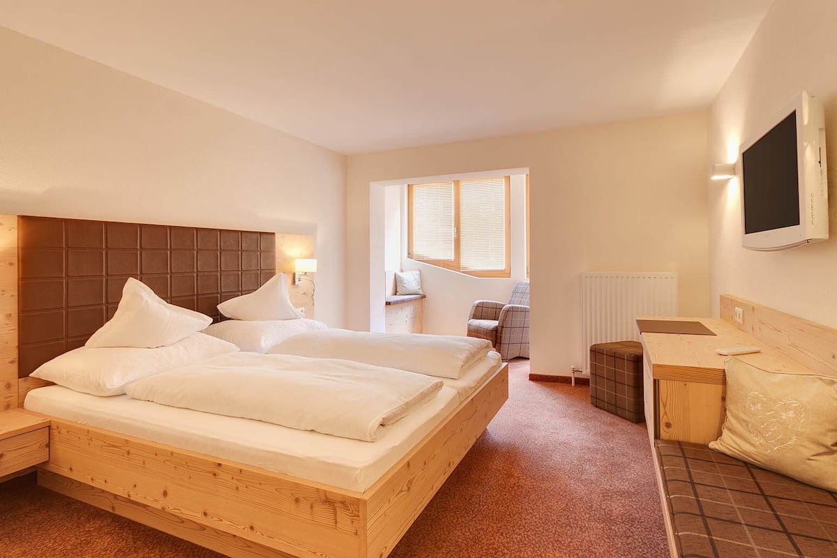 A hotel room with a large bed, a desk, a chair, and a television.