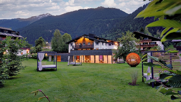 A modern house with a large glass facade, a balcony, and a well-maintained lawn. - Hotel Nova (Gaschurn)