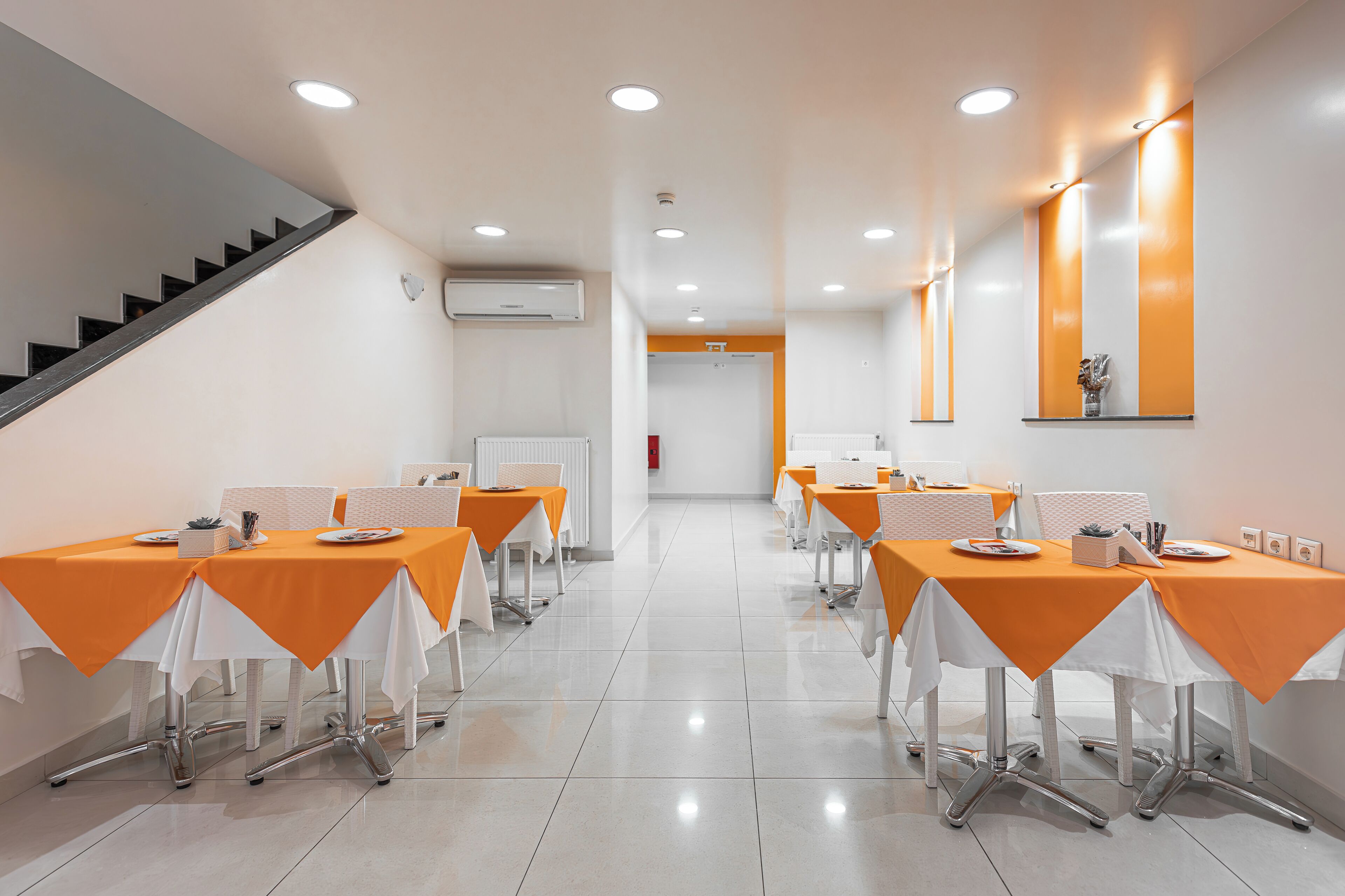 Un salón de conferencias con mesas dispuestas para reuniones, equipado con sillas y una pizarra.